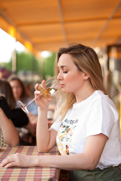 Young woman drinking a white wine in a cafe terrace with friends - Photo, image