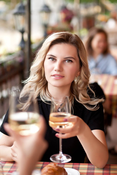 Junge Frau trinkt mit Freunden einen Weißwein auf der Caféterrasse - Foto, Bild
