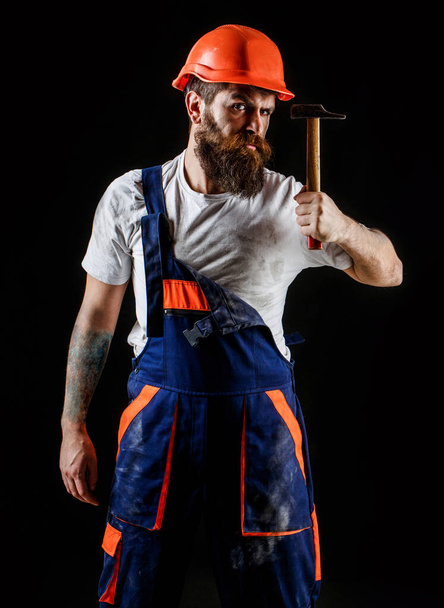 Bearded man worker with beard, building helmet, hard hat. Hammer hammering. Builder in helmet, hammer, handyman, builders in hardhat - Foto, Imagen