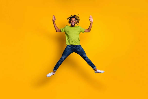 Full length photo portrait of excited guy jumping up spreading arms legs like star isolated on vivid yellow colored background - Foto, afbeelding