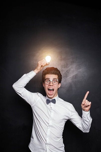 Excited nerdy man with glowing bulb having idea - 写真・画像