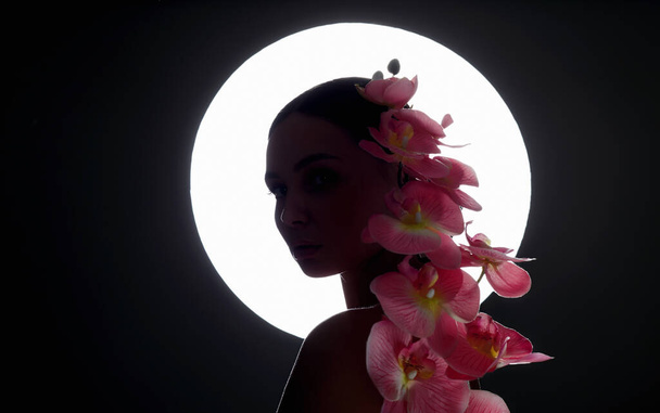Mulher nova bonita com flor do Orchid. silhueta feminina com flores no fundo da lua  - Foto, Imagem