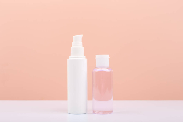 Cosmetische tubes met gezichtscrème en lotion voor het reinigen en exfoliëren van de huid tegen een felroze achtergrond  - Foto, afbeelding
