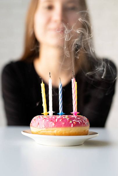 Narozeninová párty. Teenager narozeniny dívka foukání svíčky na koblihu - Fotografie, Obrázek