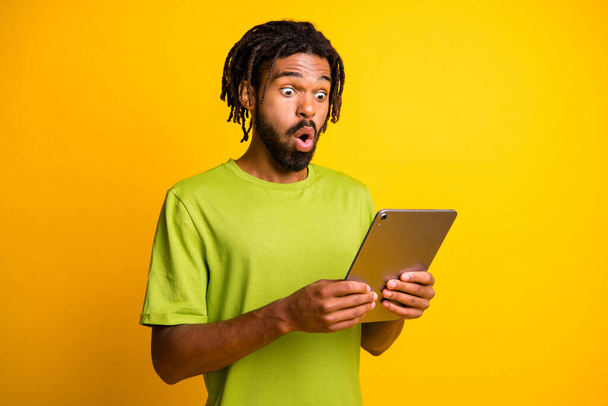 Photo of young african man hold tablet amazed shocked surprised news information isolated over yellow color background - Foto, Bild