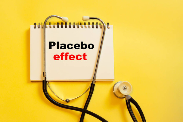 Placebo effect is a medical term on a yellow background with a stethoscope nearby. Medicine and treatment concept - Photo, image