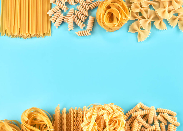 Frame from Assorted varieties of pasta wallpaper. Mix macaroni, spaghetti on blue background with copy space - Fotoğraf, Görsel
