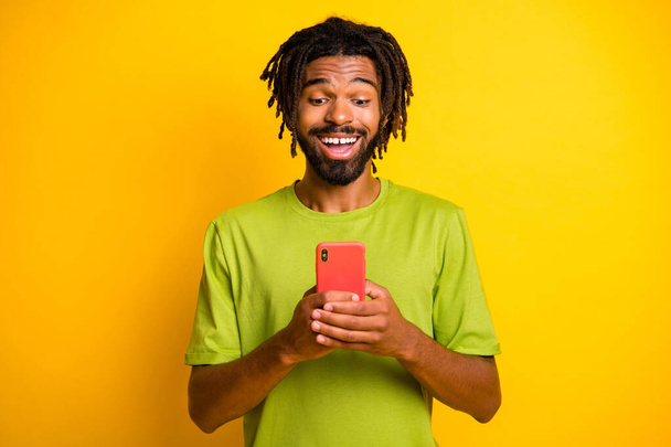 Photo of astonished dark skin guy use smartphone isolated over shine yellow color background - Valokuva, kuva