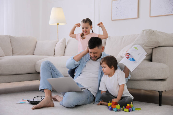 Overwhelmed man combining parenting and work at home - Zdjęcie, obraz