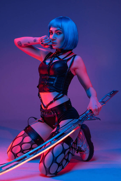 Stylish cyberpunk girl with blue hairs and glowing sword - Foto, imagen