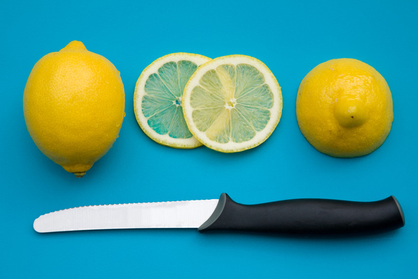 Cutting lemon - whole lemon; half; and slices on bright blue plastic cutting board - Photo, Image