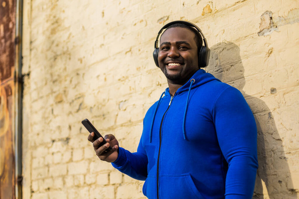 Sporty man with headphones  using mobile phone outdoor. - Foto, afbeelding