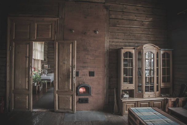 Beautiful and vintage interior of an old village house. Wooden cabinet. A door. Wooden walls. Reflection of windows in the closet. Old stove. - Foto, Imagen