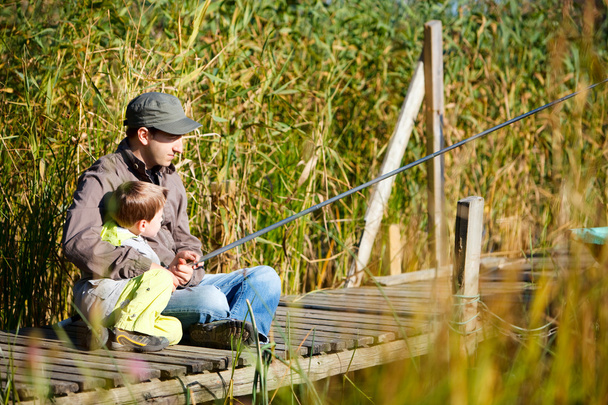 Father and small son fishing together on lake - Foto, afbeelding