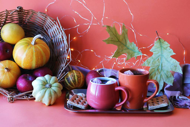 Thanksgiving day, two cups of coffee, meringues, pumpkins, apples, leaves, warm blanket on an orange background, the concept of home comfort, family holidays, autumn season  - Photo, Image