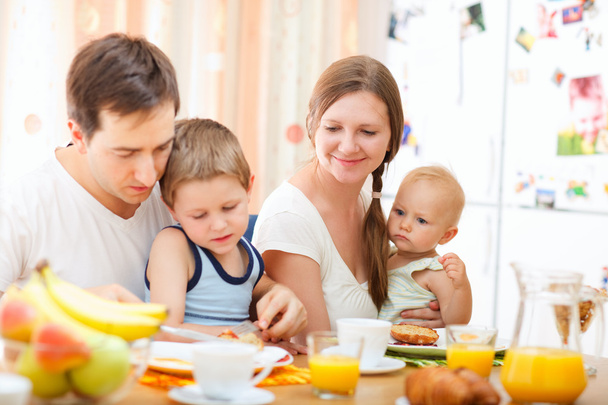 Young happy family with two kids having breakfast together - Photo, image