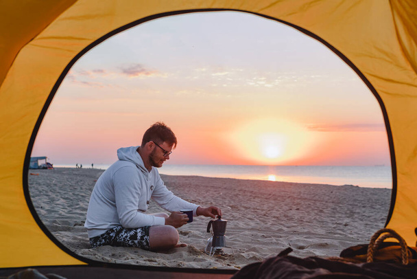 Adam deniz kumsalında kahve pişiriyor. yaz kamp tatili - Fotoğraf, Görsel
