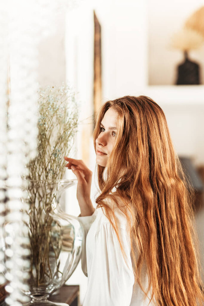 Portré egy gyönyörű fiatal lányról, hosszú hajjal, fehér ingben. Függőleges fénykép - Fotó, kép