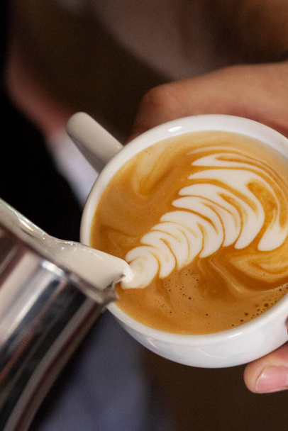 mão de barista desenhando uma imagem no copo de latte - Foto, Imagem
