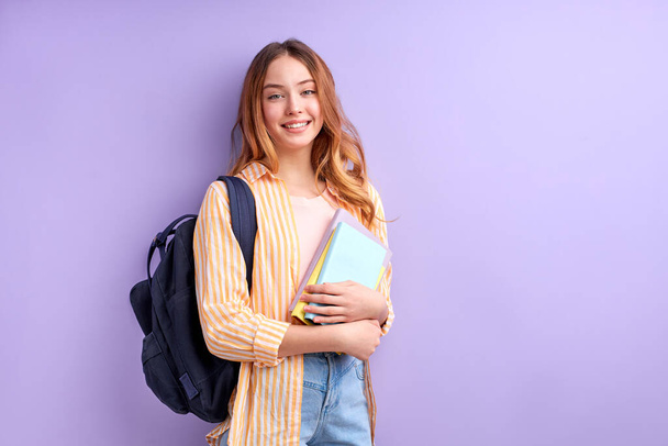 Sweet blonde student girl rejoices at new lessons,female excited about training seminar isolated on bright purple background - Zdjęcie, obraz