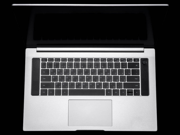 Серебряный ноутбук и клавиатура на черном фоне - Фото, изображение