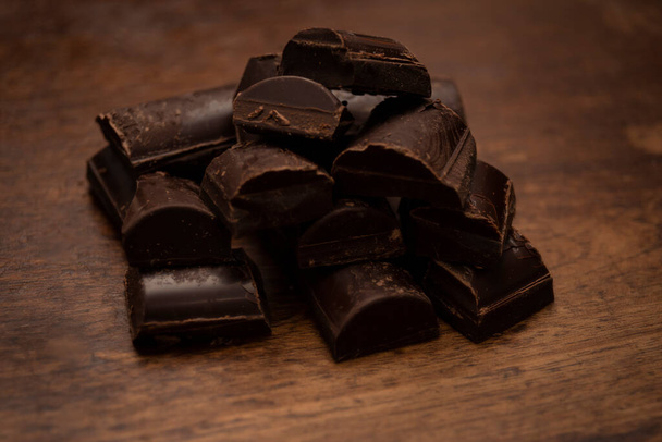 Cioccolato fondente su sfondo marrone Cioccolato amaro con arachidi in barretta su sfondo scuro con luce illuminata - Foto, immagini