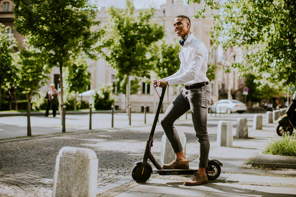 Handsome young African American using electric scooter on a street - Photo, Image