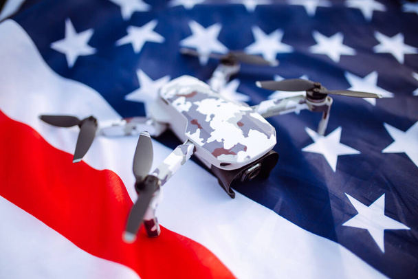 嘘をつく無人機のクローズアップショット。無人機は、小麦の緑のフィールドの背景にアメリカの旗の上にあります。独立記念日。7月4日。技術革新 - 写真・画像