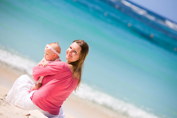 Young mother and baby girl on white sand tropical beach - Valokuva, kuva