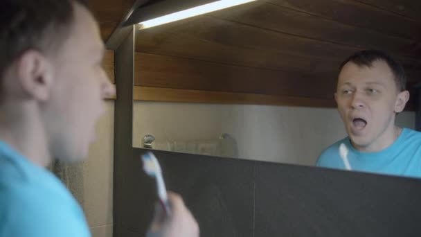 Reflejo de cerca de un hombre en el espejo, cepillarse los dientes, cuidado diario de la salud dental - Imágenes, Vídeo