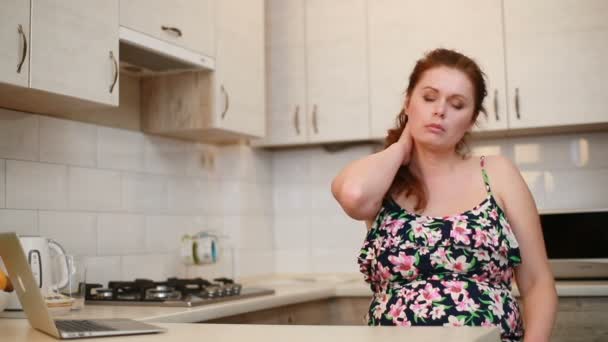 Retrato de la mujer cansada con problemas de peso haciendo auto-masaje en la cocina. - Metraje, vídeo