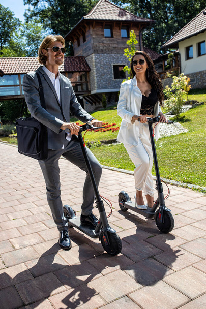 Two young businesspeople with their folding electric scooters standing on the road, no carbon emission power concept - Foto, Imagem