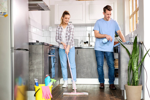 Housework,Young Couple Cleaning Home, In Kitchen. Woman Wiping Floor With Mop, Husband Helping - Valokuva, kuva