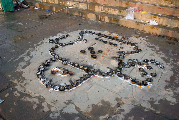 Bando de velas encharcadas ou encharcadas e diya mantidas estrategicamente no solo de cimento da margem do rio Ganges para realizar um ritual ou oração contra a vassoura em Varanasi, Uttar pradesh. - Foto, Imagem