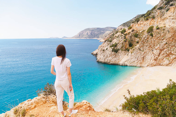 Young woman traveler looking on picturesque sea bay with beautiful Kaputas beach with turquoise water. Summer beach holiday in Turkey resort - 写真・画像