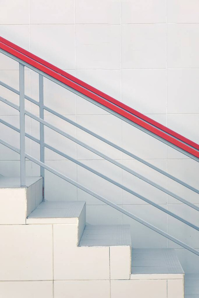 現代のタイル張りの階段または白い壁の背景に鉄ガードハンドレール付きの階段。サイドビュー。選択的フォーカス. - 写真・画像
