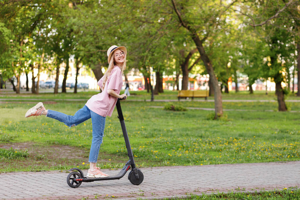 κορίτσι σε ένα ηλεκτρονικό σκούτερ σε ένα πάρκο της πόλης το καλοκαίρι - Φωτογραφία, εικόνα