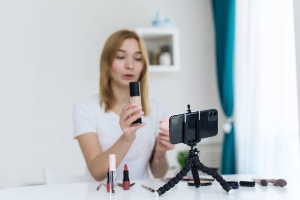 Happy souriant femme beauté vidéo blogueur enregistrement maquillage tutoriel à la maison pour son blog vidéo. Swatch de cosmétiques décoratifs - Photo, image