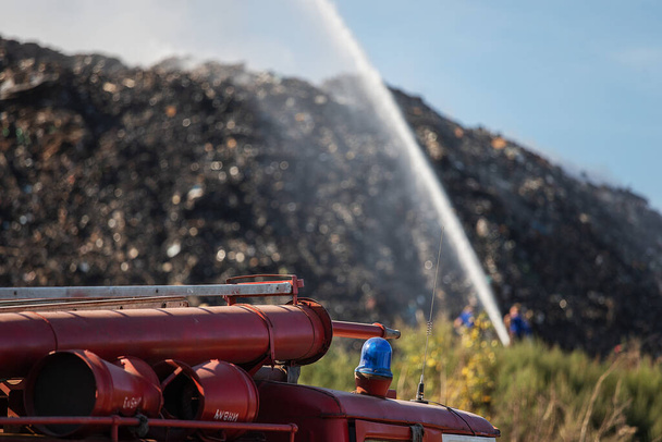 Ένα φορτηγό πετάει τόνους σκουπιδιών σε μια χωματερή. τοξικός καπνός και νέφος σε χώρους υγειονομικής ταφής επιβλαβών αποβλήτων. περιβαλλοντική καταστροφή. να σιγοκαίει σκουπίδια σε χωματερή - Φωτογραφία, εικόνα