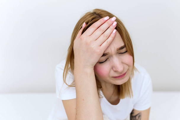 Kobieta z bólem głowy na białym tle. Młoda kobieta z migreną w domu - Zdjęcie, obraz