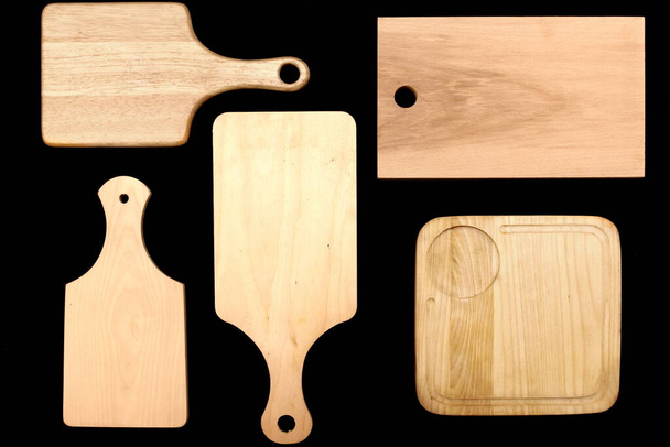 Many Wooden Cutting or Chopping Boards Isolated on Black Background. Group of Chopping Boards On Black Table. Collection of Kitchen Utensils. Overhead View. - Photo, Image