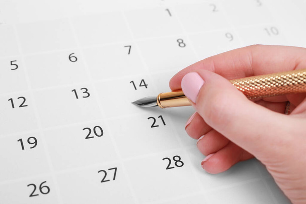 φύλλο ημερολογίου και χρυσή πένα στο χέρι, κοντινό πλάνο - Φωτογραφία, εικόνα