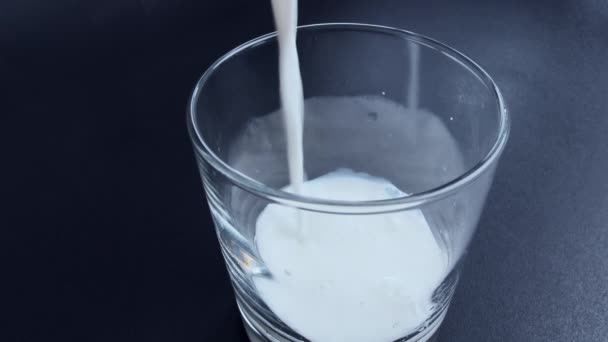 Il latte fresco è versato in un bicchiere, primo piano, vista dall'alto - Filmati, video