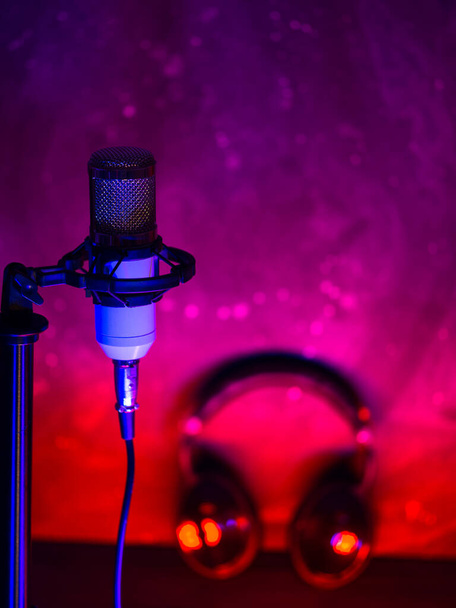 Студийный конденсатор микрофон на трибуне, наушники, цветная подвеска. Концепция звукозаписи, подкаст - Фото, изображение