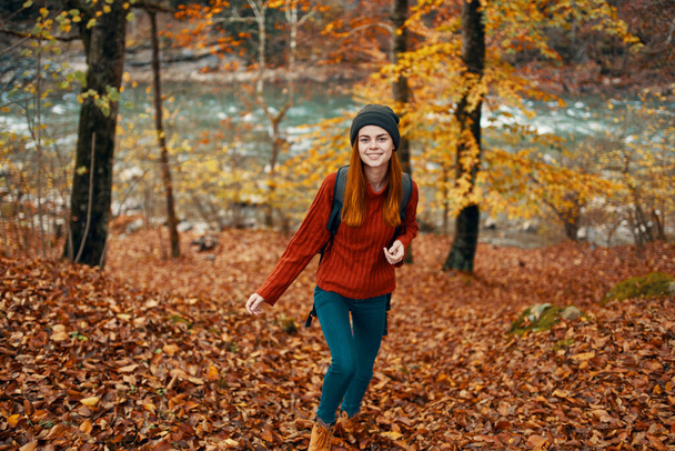 turismo de viajes mujer en suéter y jeans en el bosque de otoño cerca del río de montaña - Foto, Imagen