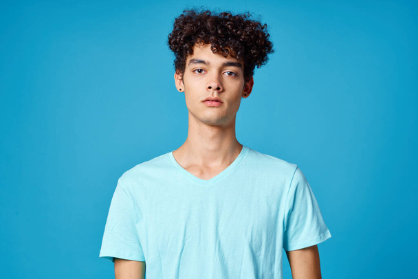 chico en azul camiseta rizado pelo recortado vista aislado fondo - Foto, Imagen