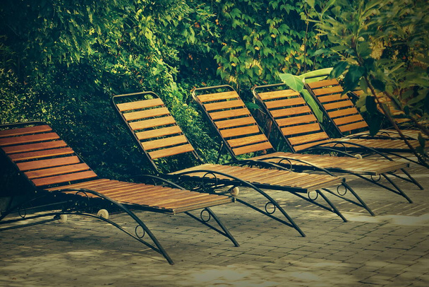 Wooden Chaise Lounges or Sunbeds in Garden Patio At Pool Дерев'яні стільці або планкові ліжка на бетоні. Сонячні ліжка на задньому дворі. - Фото, зображення