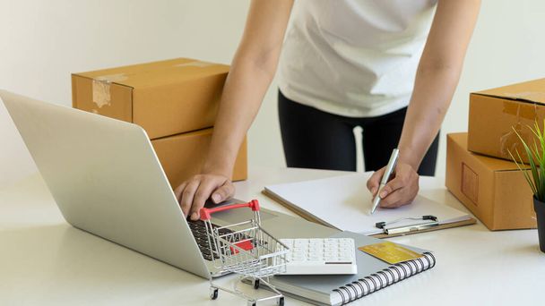 Владельцы малого бизнеса, работающие с ноутбуками и картонными коробками на работе - Фото, изображение