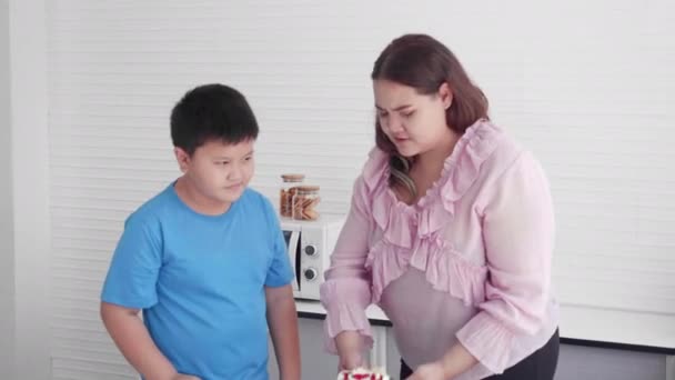 Asiatische Familienbeziehung mit Sohn verbietet Mutter Fett essen Kuchen in der Küche zu Hause, Mutter ungesundes Essen, zwei Personen, Frau übergewichtig, Muttertag, Gesundheitsversorgung, Urlaubskonzept. - Filmmaterial, Video