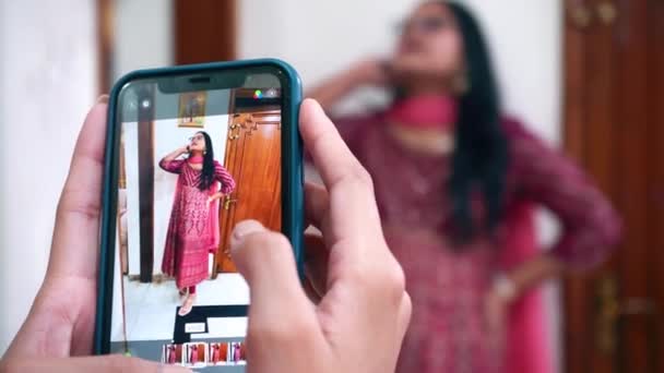 インドのアグラでスマートフォンを使って誰かと一緒に彼女の写真を撮るインドの女の子-中程度のショット - 映像、動画